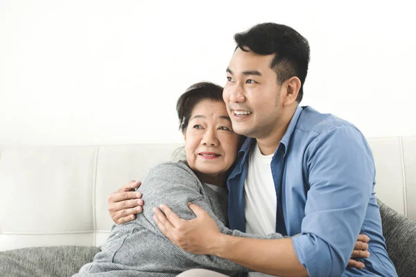 Aziatische moeder knuffelen haar zoon en zittend op de Bank thuis, bovenlichaam — Stockfoto