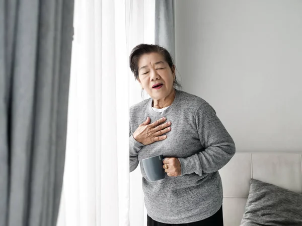 Asiática senior mujer having heart attack mientras permaneciendo en casa alo —  Fotos de Stock