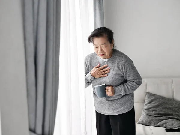 Asiática senior mujer having heart attack mientras permaneciendo en casa alo —  Fotos de Stock