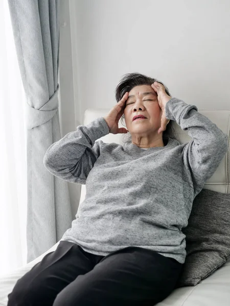 Asiatiska Senior kvinna har huvudvärk hemma, hälso-och sjukvård koncept. — Stockfoto