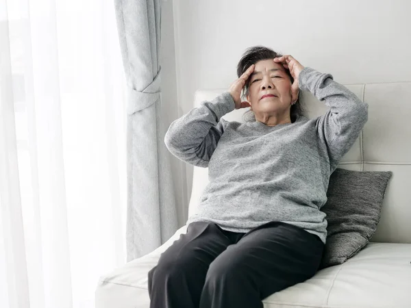 Aziatische Senior vrouw met hoofdpijn thuis, gezondheidszorg concept. — Stockfoto