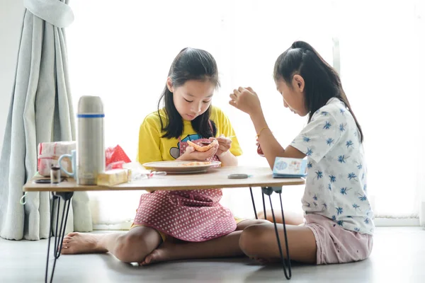 Asiatisk syster sprider jordgubbs sylt på bröd för hennes yngre s — Stockfoto