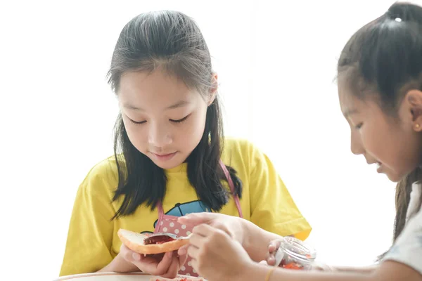 Asian siostra rozprzestrzeniania truskawka Jam na chleb dla jej młodszy s — Zdjęcie stockowe