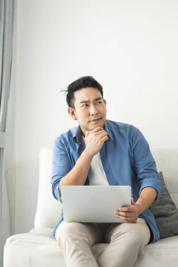 Stresli Asyalı adam evde dizüstü bilgisayar kullanarak, yaşam tarzı kavramı ile 