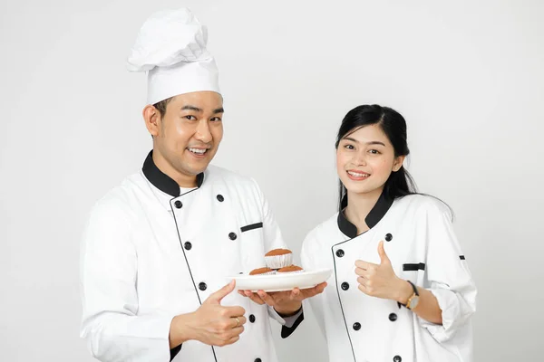 Pulgar hacia arriba los chefs de pastelería con cupcakes en el plato blanco y checki — Foto de Stock