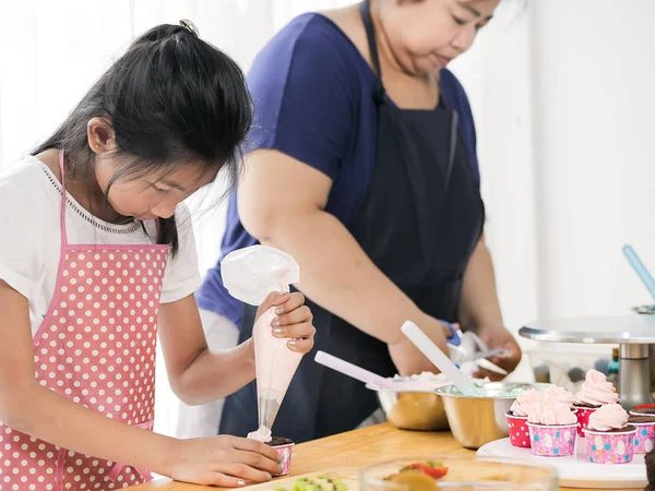 Азиатская девушка учится со своей матерью, готовясь украсить дом — стоковое фото