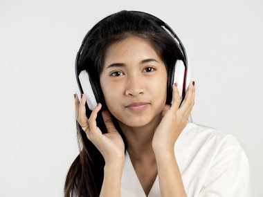 Asyalı genç kız kulaklık kullanarak ve kamera bakarak.