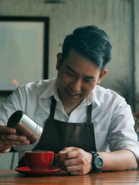 Asyalı barmen kırmızı bardağa çikolata tozu serper..