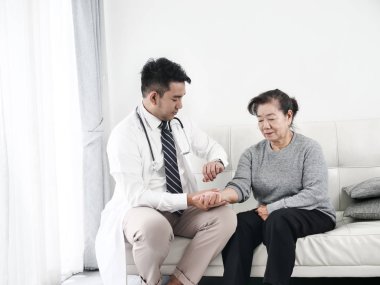 Asyalı doktor ofiste onun hasta yaşlı kadın kontrol.