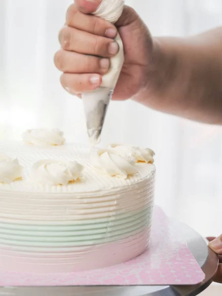Konditor belegt Kuchen mit Sahne mit einer Teigtasche, — Stockfoto