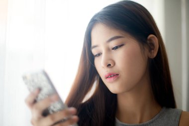 Smartphone ile pencere ışık kullanarak çekici Asyalı kadın.