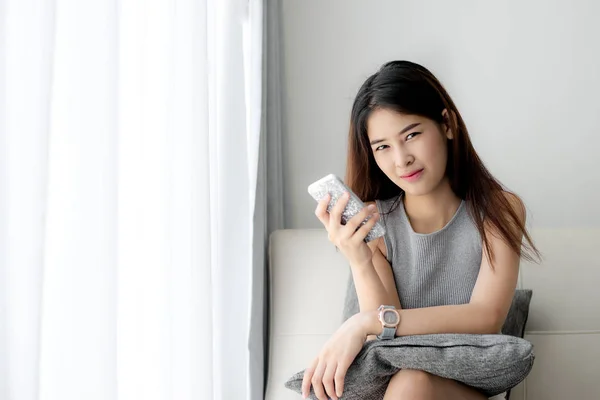 Mulher asiática relaxante no sofá e usando telefone inteligente em casa, vida — Fotografia de Stock