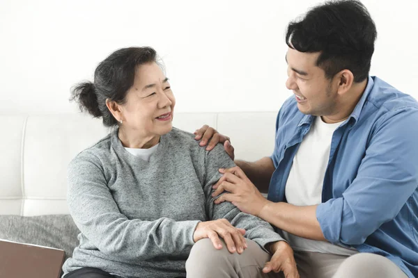 Asyalı adam evinde annesine masaj yapıyor, yaşam tarzı konsepti..