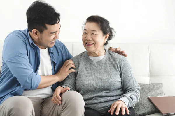 Asyalı adam evinde annesine masaj yapıyor, yaşam tarzı konsepti..