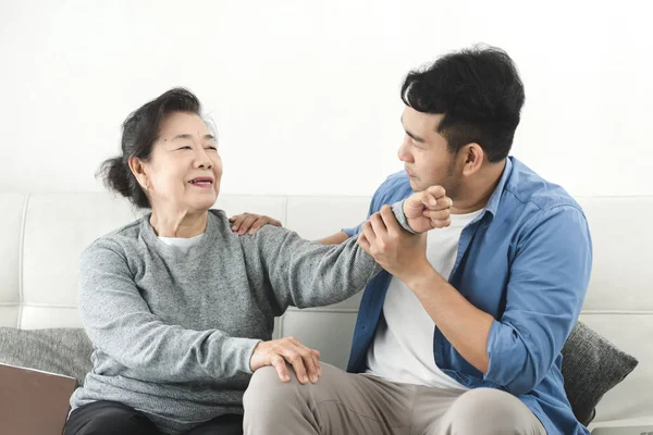 Asyalı adam evinde annesine masaj yapıyor, yaşam tarzı konsepti..