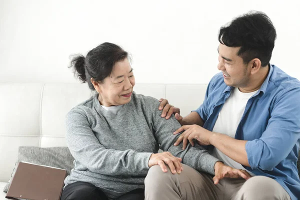 Asyalı adam evinde annesine masaj yapıyor, yaşam tarzı konsepti..