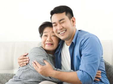 Asyalı anne oğluna sarılma ve evde kanepede oturan, lifest