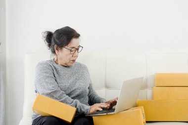 Packag ile online satış yaparken dizüstü bilgisayar kullanan Asyalı yaşlı kadın