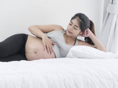 Asyalı hamile kadın evde, yatağında yaşam tarzı kavramı dinlenme.