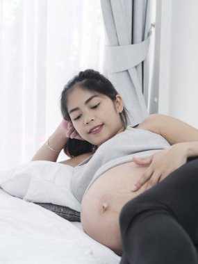 Asyalı hamile kadın evde, yatağında yaşam tarzı kavramı dinlenme.