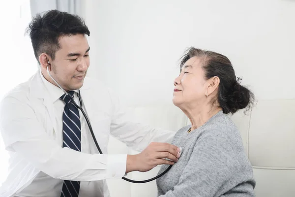 Asiatische Arzt Überprüfung bis seine geduldige alte Frau in Büro. — Stockfoto