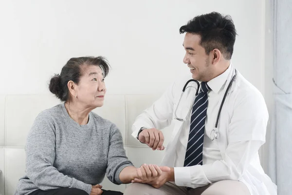 Asiatische Arzt Überprüfung bis seine geduldige alte Frau in Büro. — Stockfoto