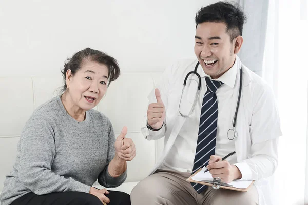 Asiatische Arzt und Senior Patient mit Daumen hoch Hände unterzeichnen, heilen — Stockfoto