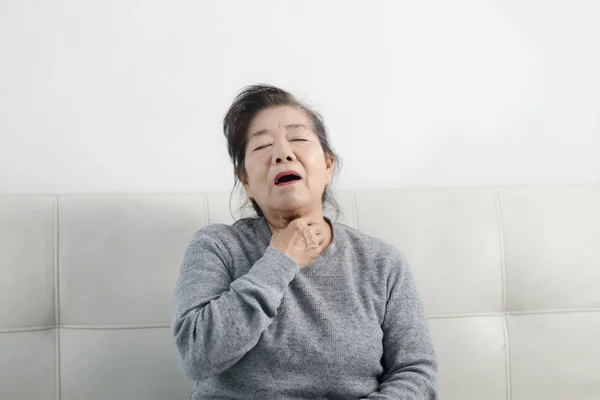 Starší asijská žena si kašle, když sedí na pohovce, životní styl — Stock fotografie