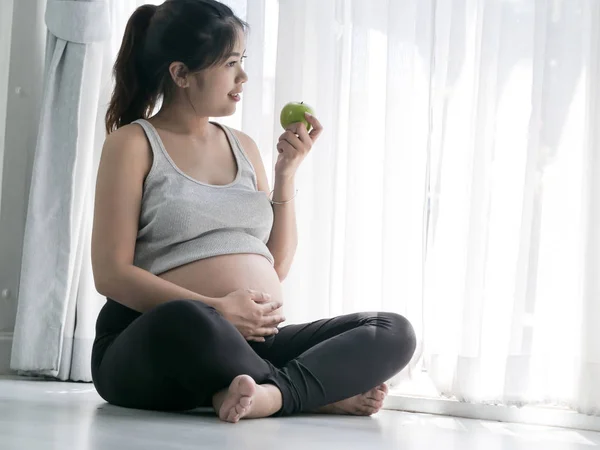 Счастливая азиатская женщина держит зеленое яблоко в руке и сидит на — стоковое фото