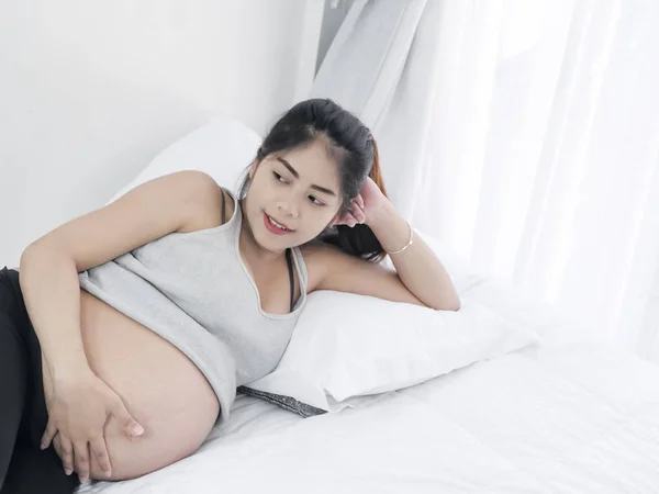 Азиатская беременная женщина отдыхает на кровати дома, концепция образа жизни . — стоковое фото