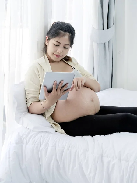 Asiatico donna incinta utilizzando tablet sul letto a casa, stile di vita conc — Foto Stock