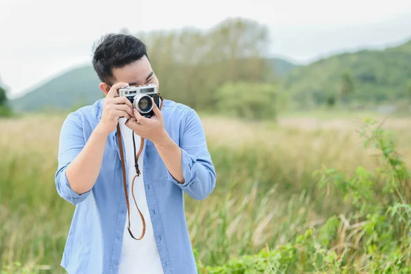 Fotógrafo asiático com câmera vintage tirando fotos na natureza — Fotografia de Stock