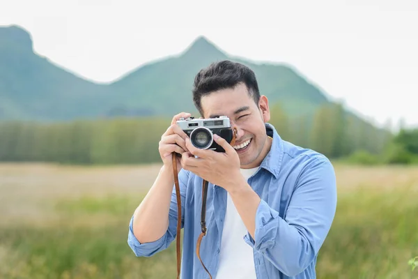 Fotógrafo asiático com câmera vintage tirando fotos na natureza — Fotografia de Stock