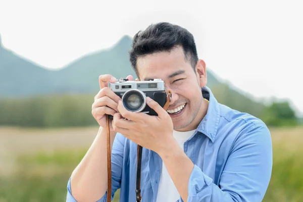 Fotógrafo asiático con cámara vintage tomando fotos en la naturaleza — Foto de Stock