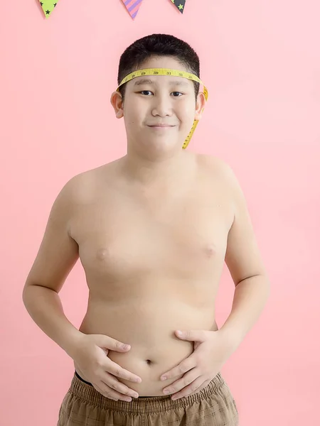 Asiatische Junge mit seinem Bauch mit einem Maßband auf einem rosa Hintergrund — Stockfoto