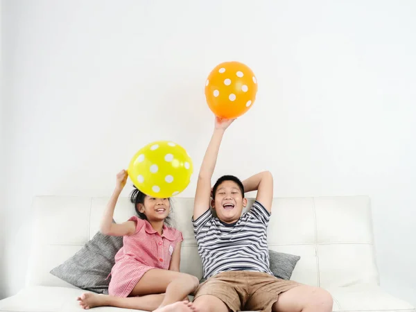 Asiática irmã e seu irmão jogando balões em casa juntos , — Fotografia de Stock