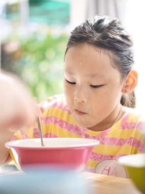 Şirin Asyalı kız pirinç çorbası kahvaltıda yiyor.