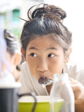 Şirin Asyalı kız pirinç çorbası kahvaltıda yiyor.