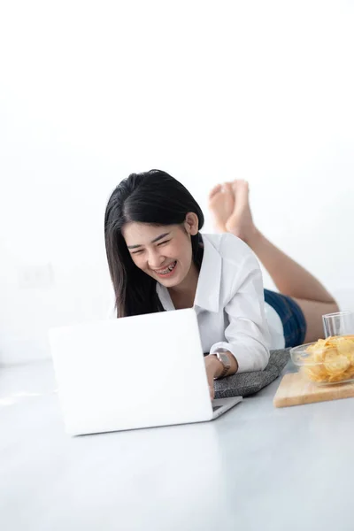 Азиатская женщина в белой рубашке, лежащая на полу и использующая ноутбук на h — стоковое фото