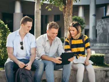 Mutlu üniversite öğrencisi bina dışında birlikte tablet kullanarak 
