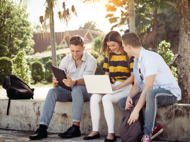 Mutlu üniversite öğrencisi bina dışında birlikte dizüstü bilgisayar kullanarak 