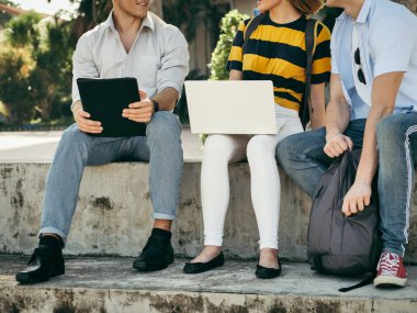 Mutlu üniversite öğrencisi bina dışında birlikte dizüstü bilgisayar kullanarak 