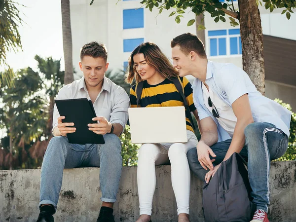 Onnellinen yliopiston opiskelija käyttää kannettavaa tietokonetta yhdessä rakennuksen ulkopuolella — kuvapankkivalokuva