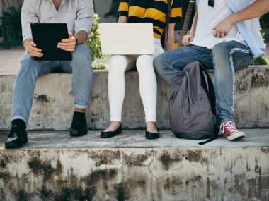 Mutlu üniversite öğrencisi bina dışında birlikte dizüstü bilgisayar kullanarak 