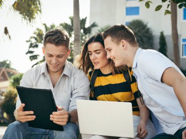 Mutlu üniversite öğrencisi bina dışında birlikte dizüstü bilgisayar kullanarak 