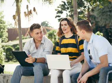 Mutlu üniversite öğrencisi bina dışında birlikte dizüstü bilgisayar kullanarak 