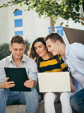 Mutlu üniversite öğrencisi bina dışında birlikte dizüstü bilgisayar kullanarak 