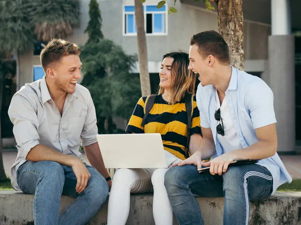 Naurava yliopisto-opiskelija käyttää tabletti yhdessä ulkopuolella buildi — kuvapankkivalokuva