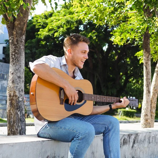 Campus student spelar gitarr utomhus, livsstil Concept. — Stockfoto