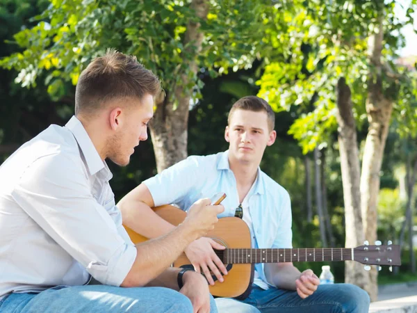 Campus student pratar och spelar gitarr utomhus, Lifestyle con — Stockfoto